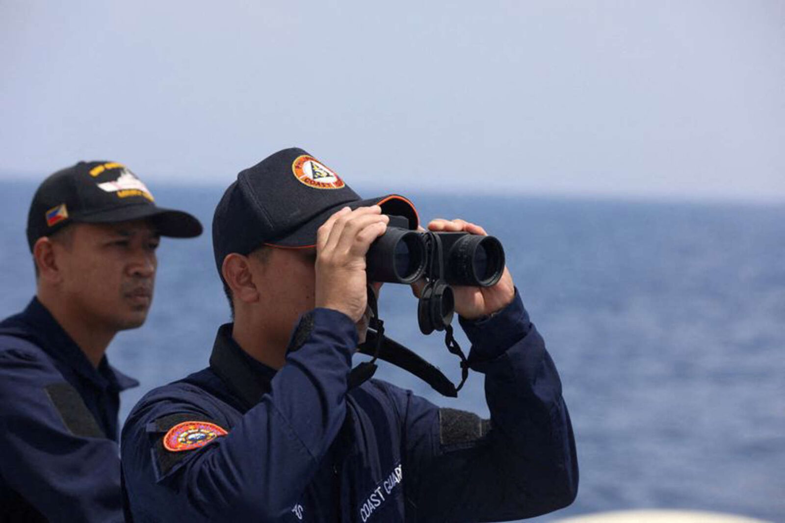 A member of the Philippine coast guard looks through binoculars during a mission to resupply troops stationed on a ship anchored in the South China Sea